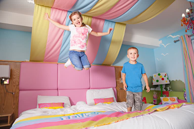 Two children bouncing on a bed in the Swizzels suite