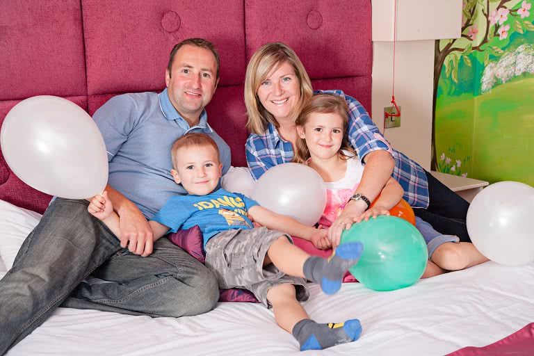 A family with balloons on the bed in a princess suite